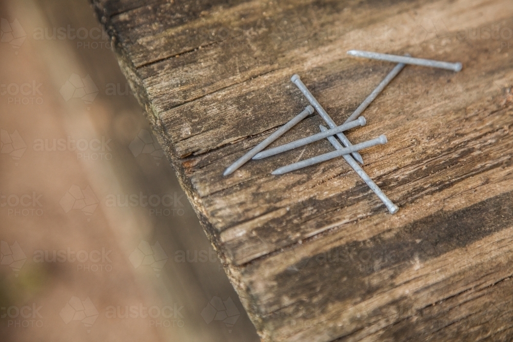 Scattered nails on wooden background - Australian Stock Image