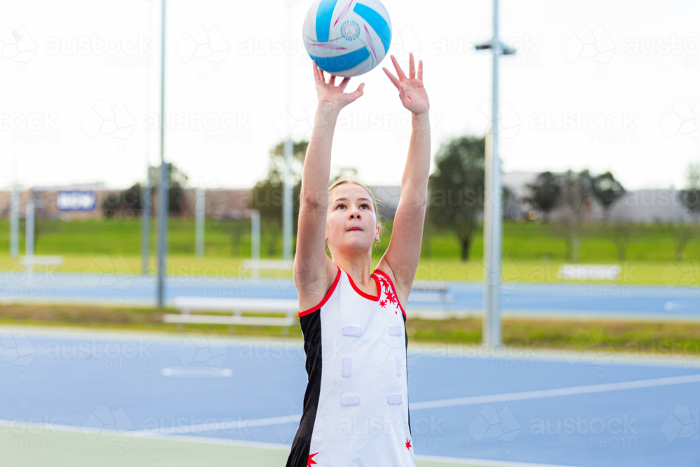 School aged netball player catching ball on court - Australian Stock Image