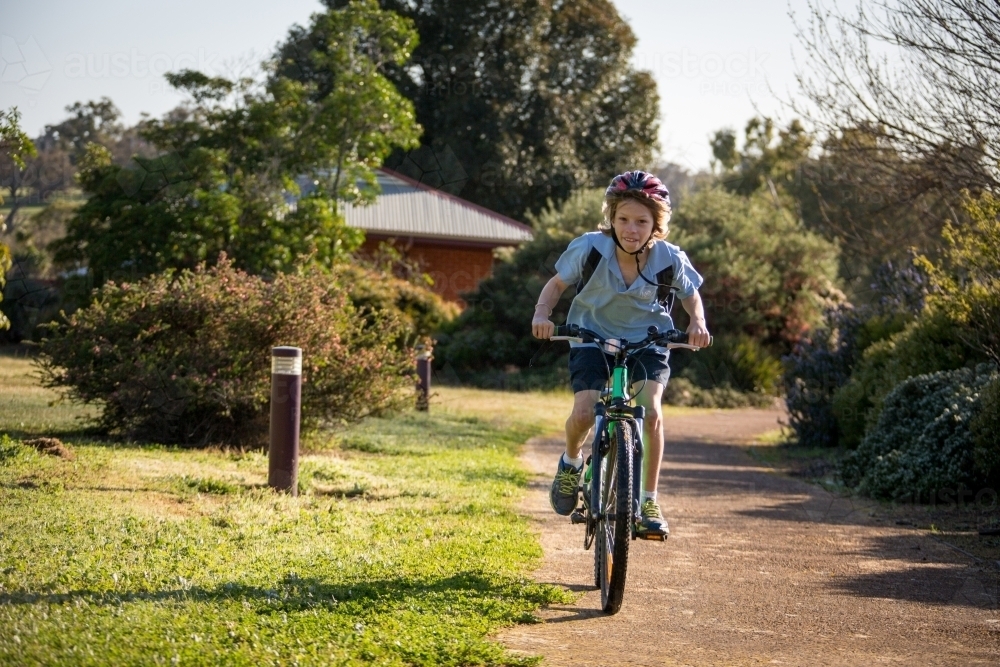 School boy riding his bike home from school - Australian Stock Image