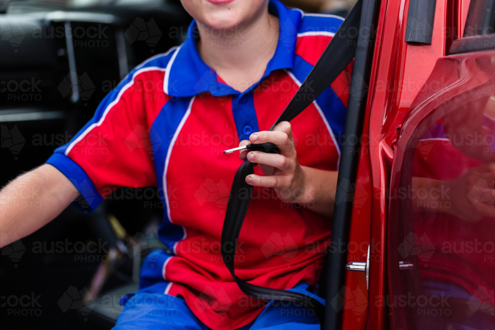 school child holding buckle of lap and sash belt ready to get buckled into car - Australian Stock Image