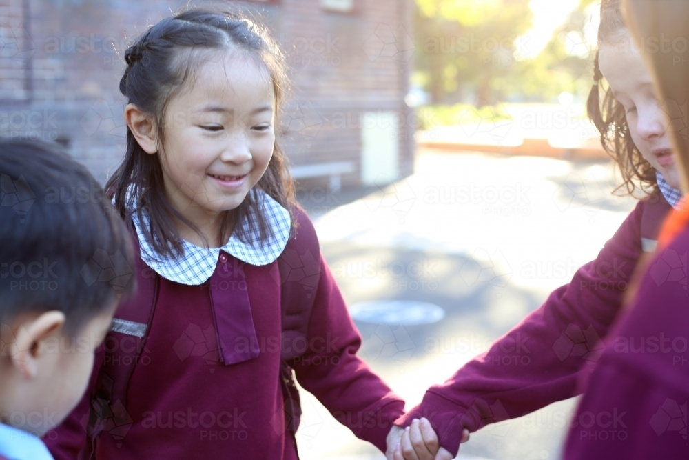 School children holding hands and playing in the playground - Australian Stock Image