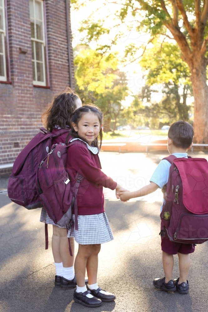 School children holding hands walking in the school yard - Australian Stock Image