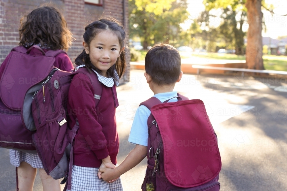 School children holding hands walking in the school yard - Australian Stock Image