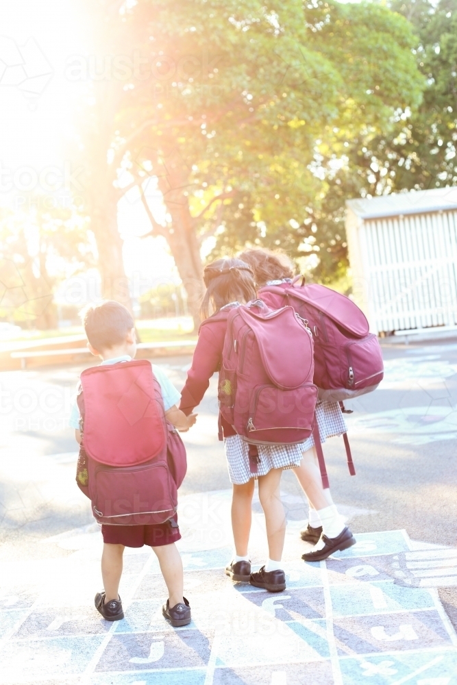 School children holding hands, walking out of school in the afternoon light - Australian Stock Image