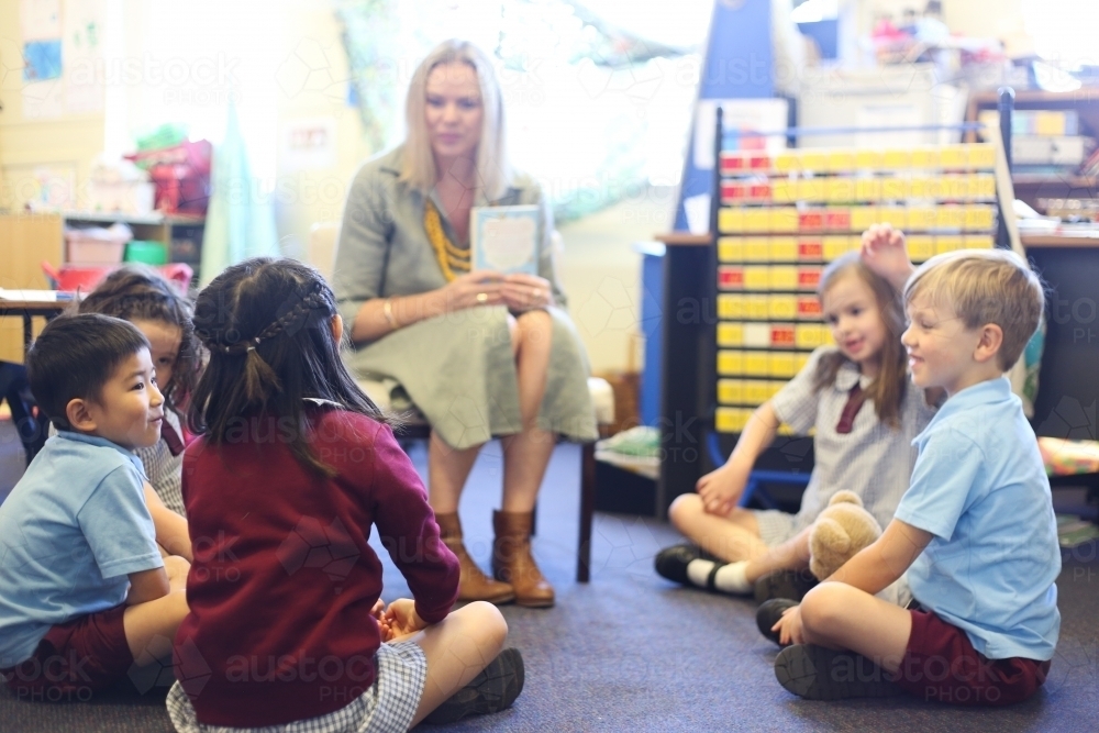 School children sitting on floor, talking with their teacher - Australian Stock Image