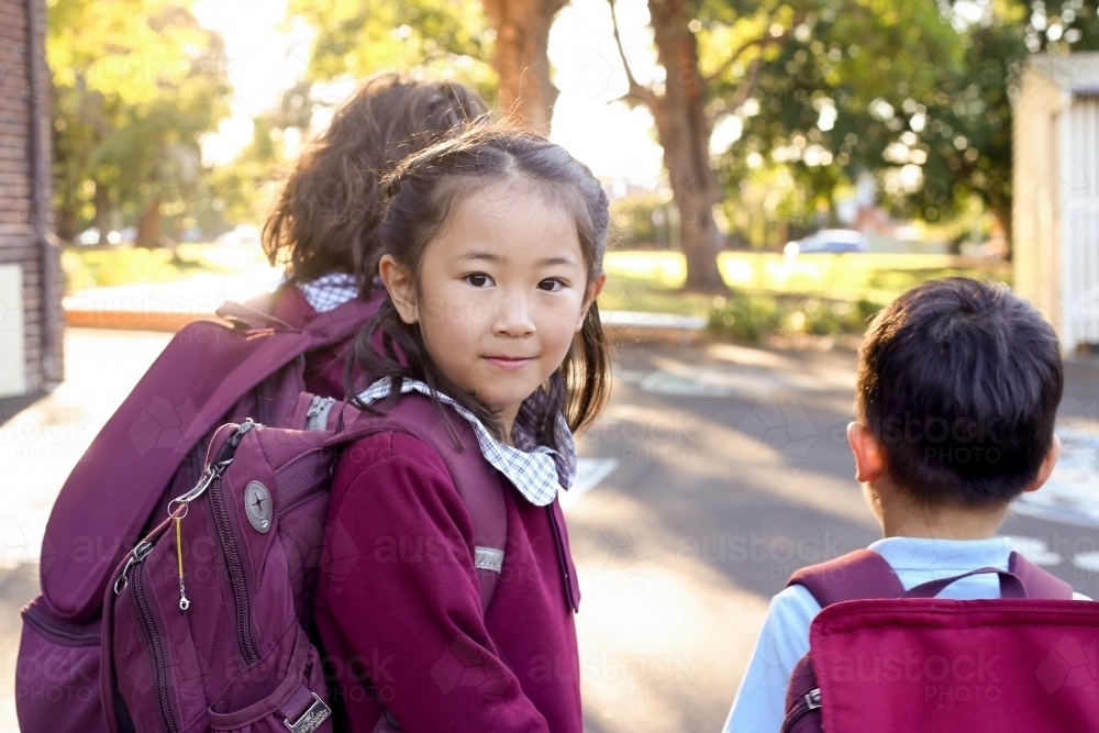 School children walking through school playground with backpacks on - Australian Stock Image