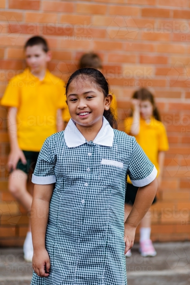School girl in green and white check public school dress outside classroom - Australian Stock Image