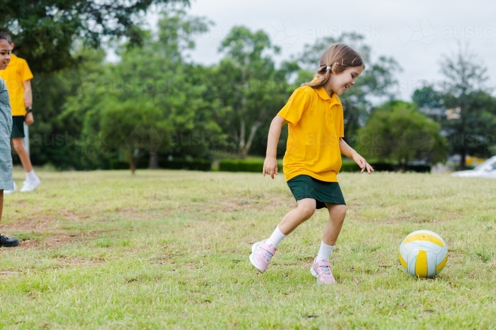 School girl playing sports with ball on grass - Australian Stock Image