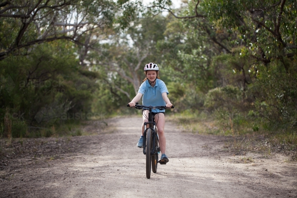 School girl riding a mountain bike on a bush trail - Australian Stock Image
