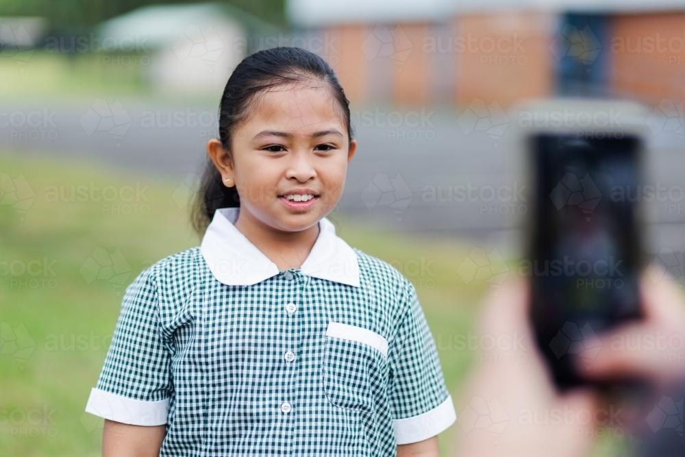 School girl standing for her mum to take her photo on her first day back to school - Australian Stock Image