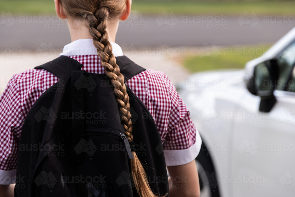 school girl walking to the car wearing uniform and with a backpack on - Australian Stock Image