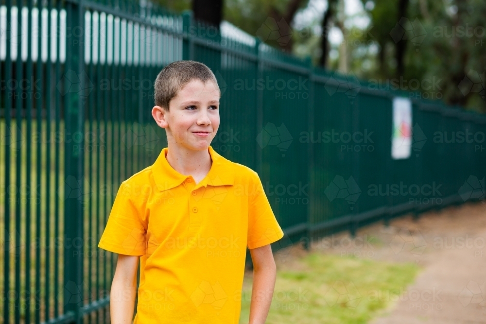 School kid in yellow polo shirt looking to the side at copy space - Australian Stock Image