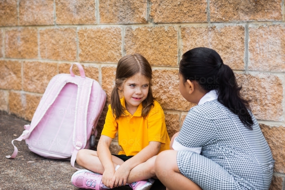 School kids sitting by a wall chatting together - Australian Stock Image