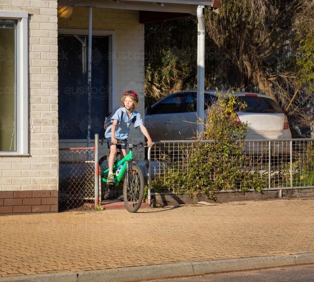 Schoolboy leaving home on bicycle - Australian Stock Image