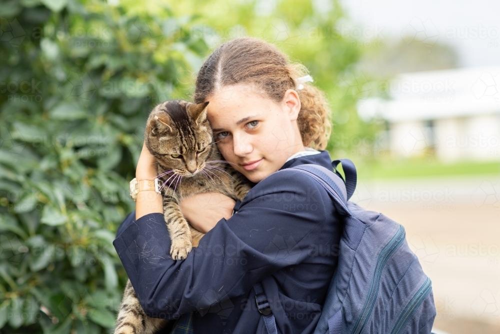Schoolgirl cuddling tabby cat - Australian Stock Image