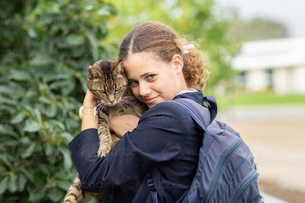 Schoolgirl cuddling tabby cat - Australian Stock Image