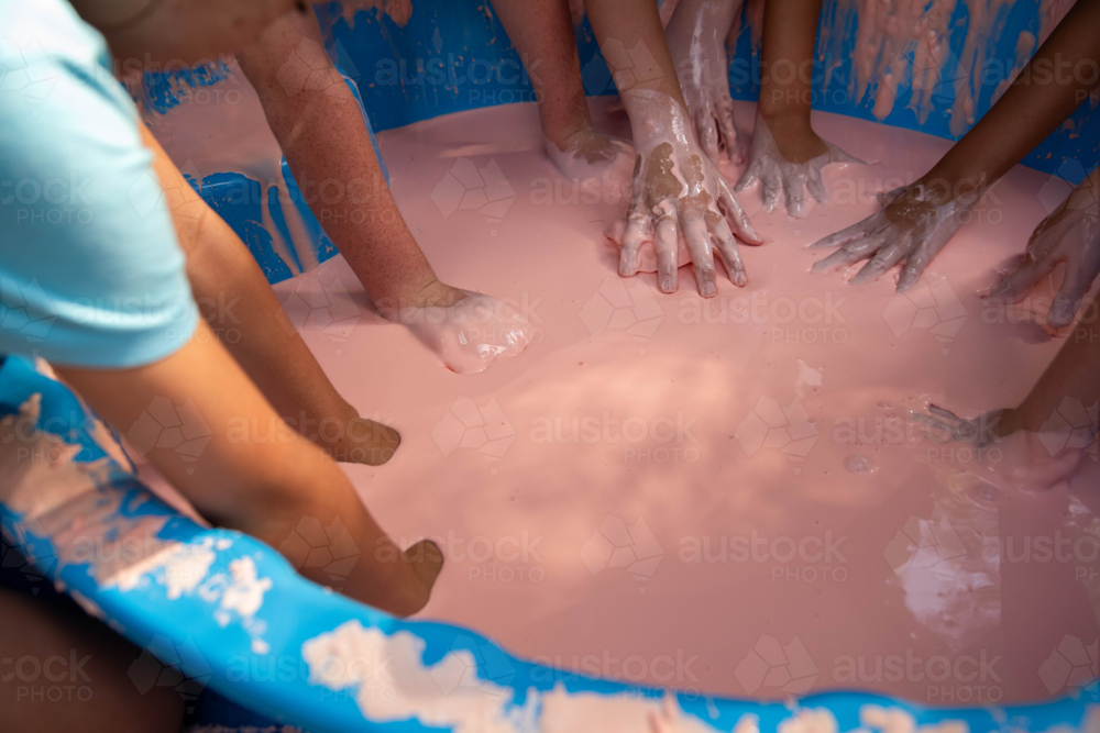 Science experiment with children dipping hands into oobleck, cornstarch and water mixture - Australian Stock Image