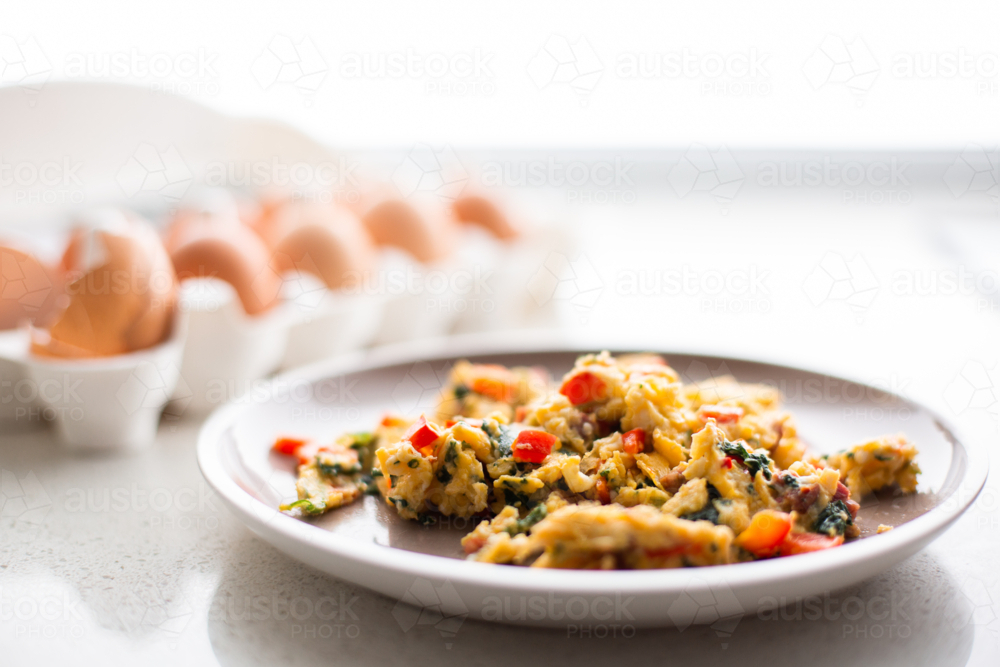 Image of scrambled eggs with spinach and tomato on a plate - Austockphoto