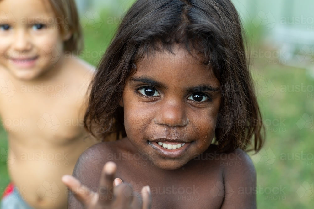 scruffy little kid with big brown eyes and dark hair smiling - Australian Stock Image