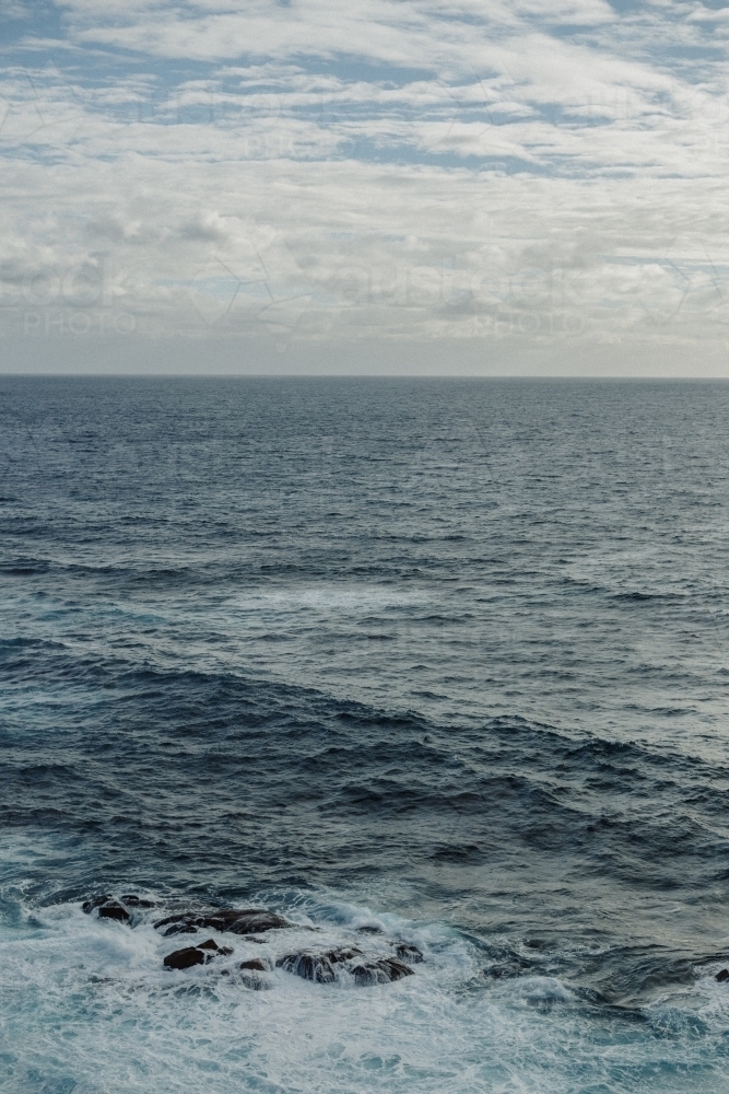 Sea with flat horizon on overcast day, white wash in foreground - Australian Stock Image