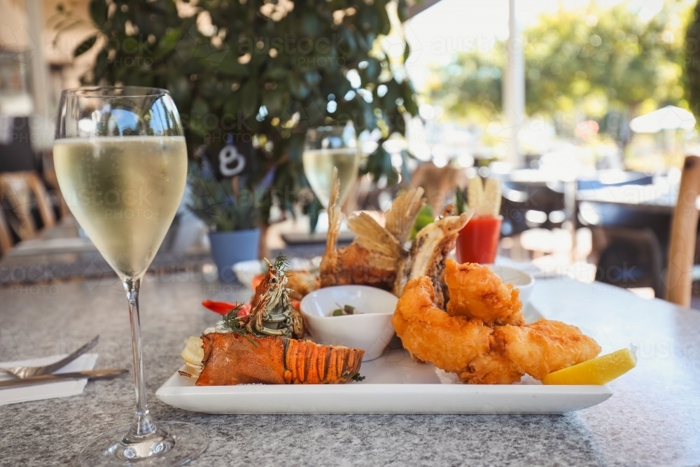 Seafood platter in alfresco dining setting featuring squid, prawns and barramundi wings - Australian Stock Image