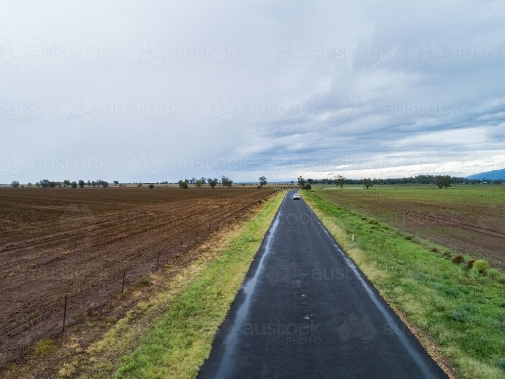 Sealed country road through brown ploughed farmland - Australian Stock Image