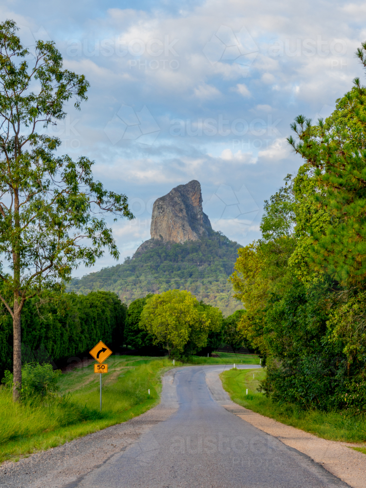 Sealed road through green bushland leading to mountain peak in background - Australian Stock Image