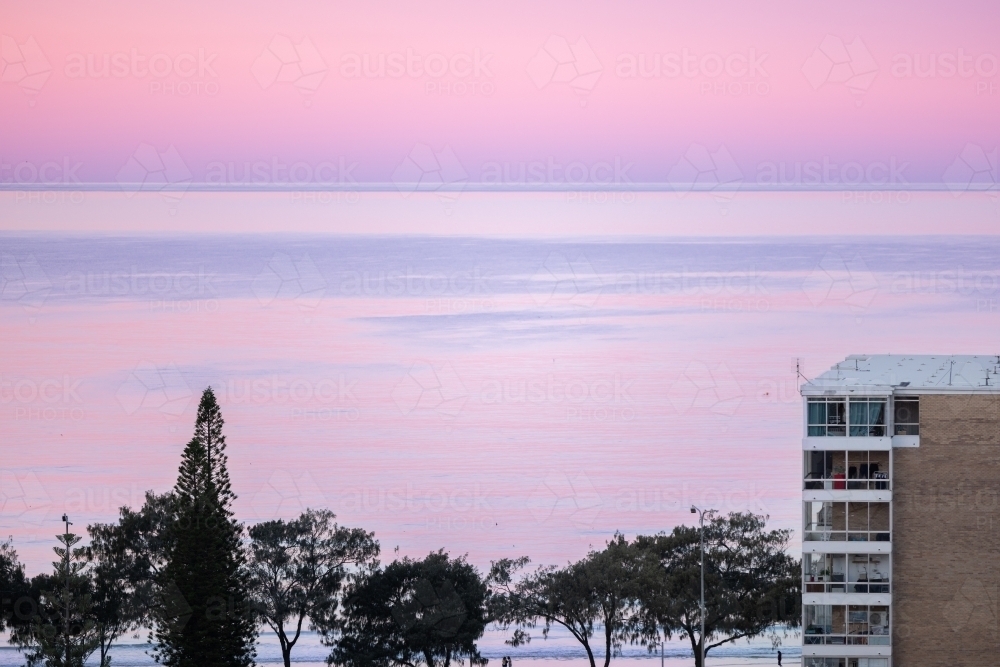 Seaside highrise apartment near the beach with pink sky at sunset - Australian Stock Image