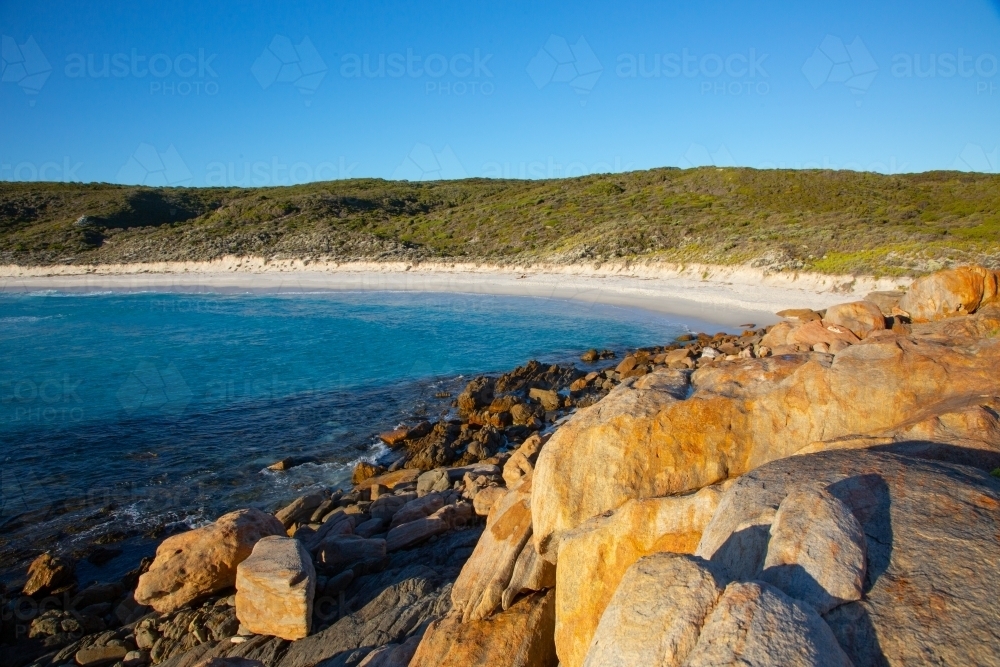 Seaside scene with light on orange rocks - Australian Stock Image