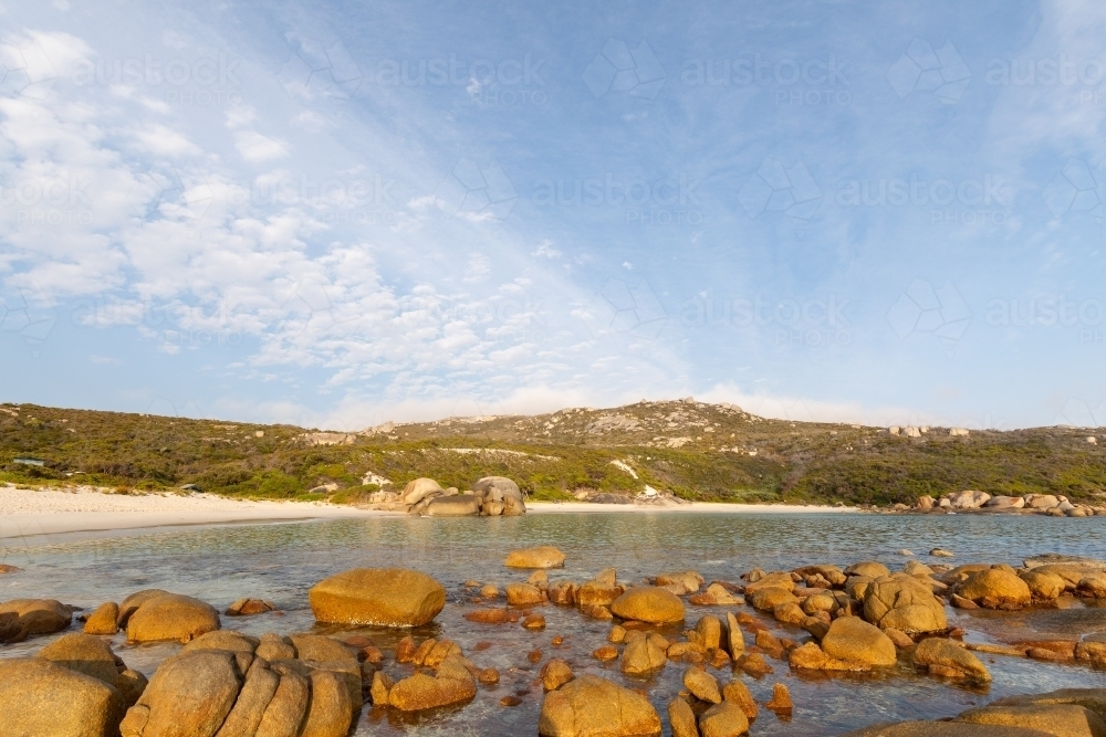 secluded white sand beach with rocks in foreground - Australian Stock Image