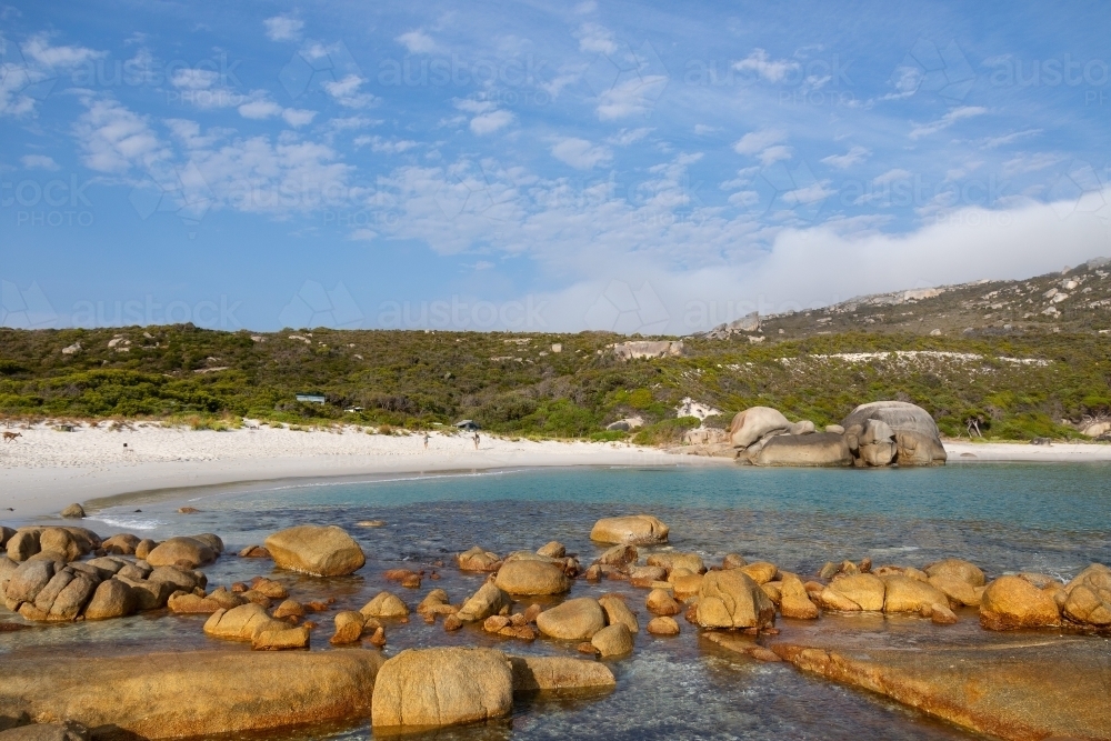 secluded white sand beach with rocks in foreground - Australian Stock Image