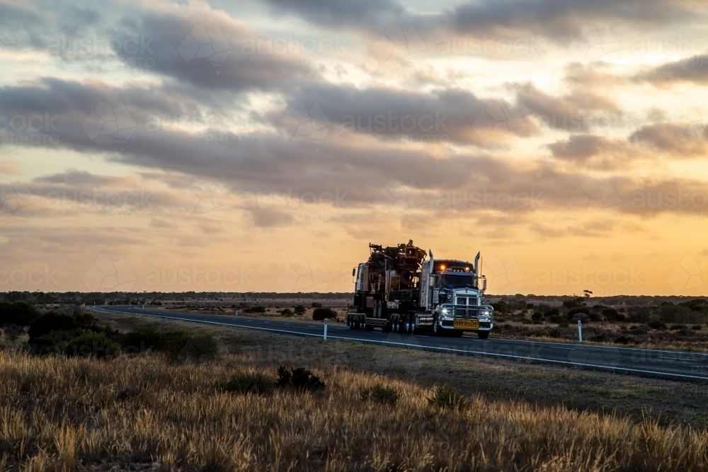 Semi trailer truck driving at dusk on Eyre Highway along the Nullarbor Plain - Australian Stock Image