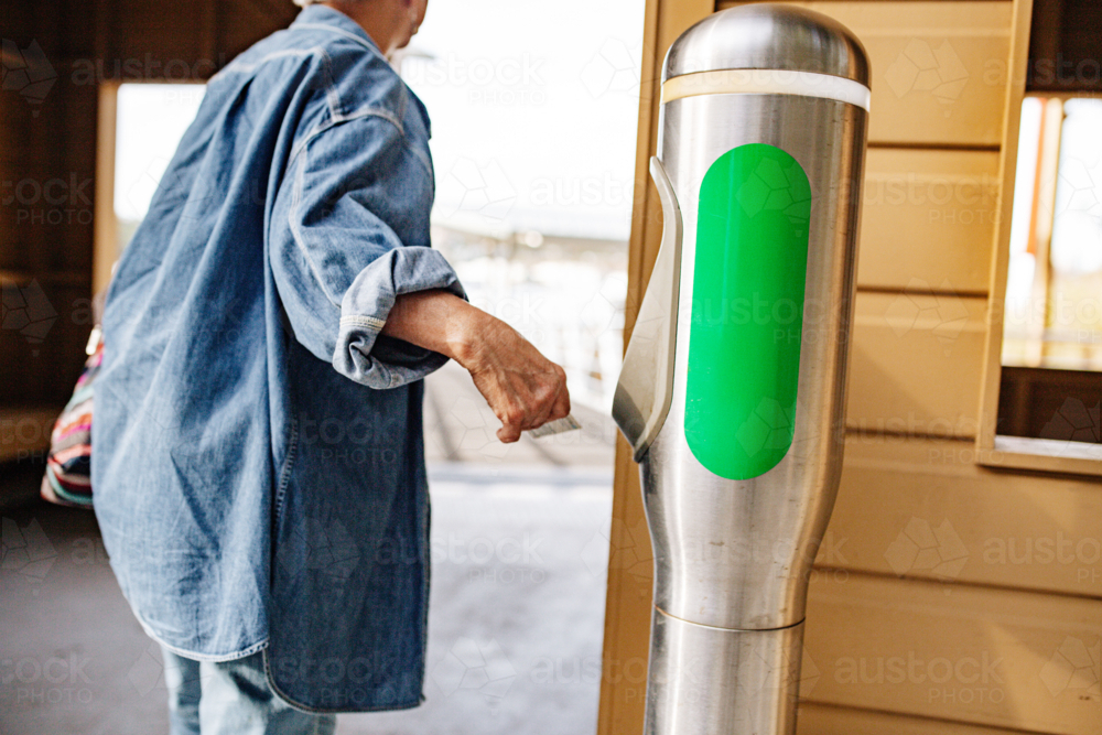 Senior Asian woman walking away from tap off machine - Australian Stock Image