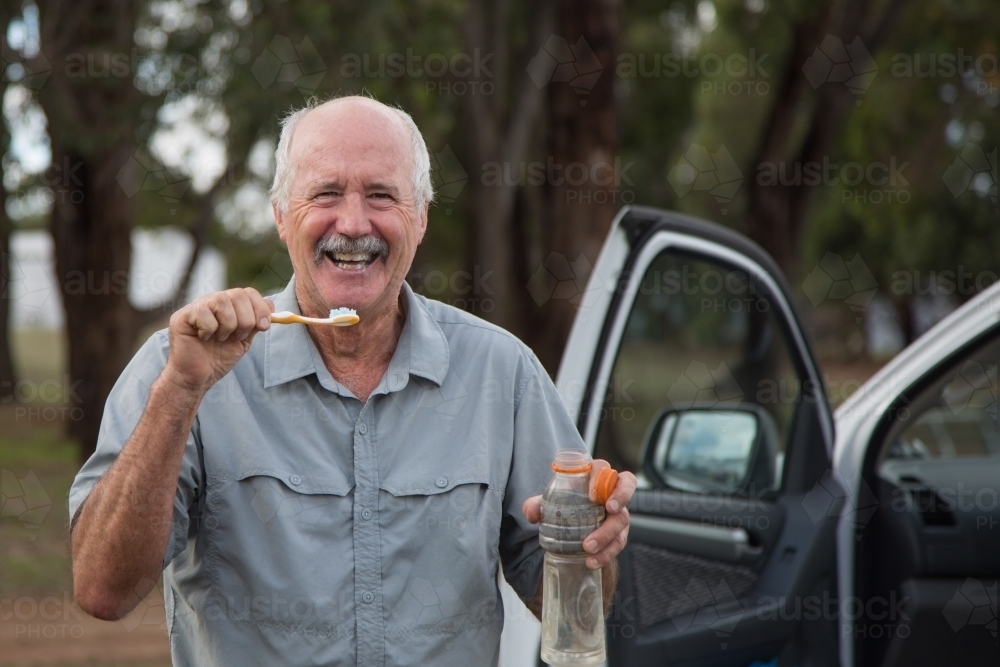 Senior gentleman brushing teeth in the bush - Australian Stock Image