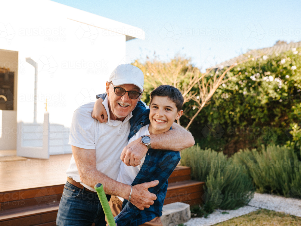 Senior guy hugging a young boy outside the house. - Australian Stock Image