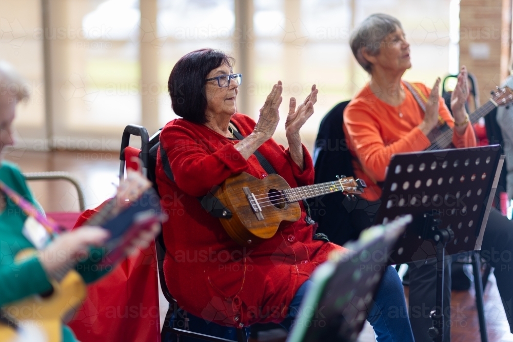 senior ladies with ukuleles applauding - Australian Stock Image