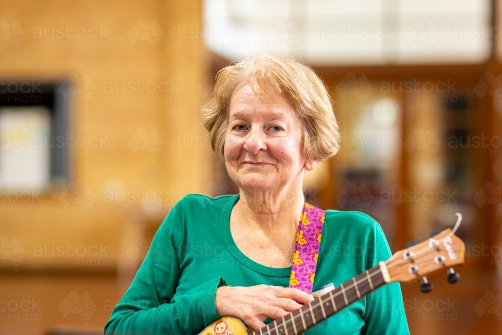 senior lady holding a with ukulele smiling - Australian Stock Image