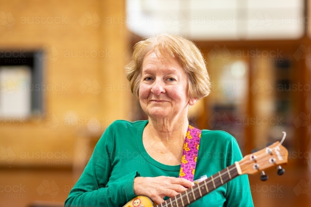 senior lady looking at camera with ukulele - Australian Stock Image