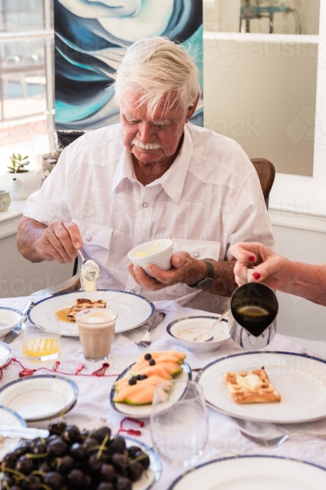 senior man enjoying brunch on xmas morning - Australian Stock Image