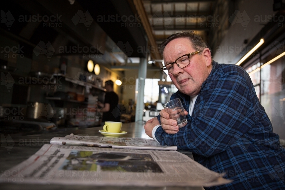 Senior Man Reading Newspaper in Coffee Shop - Australian Stock Image