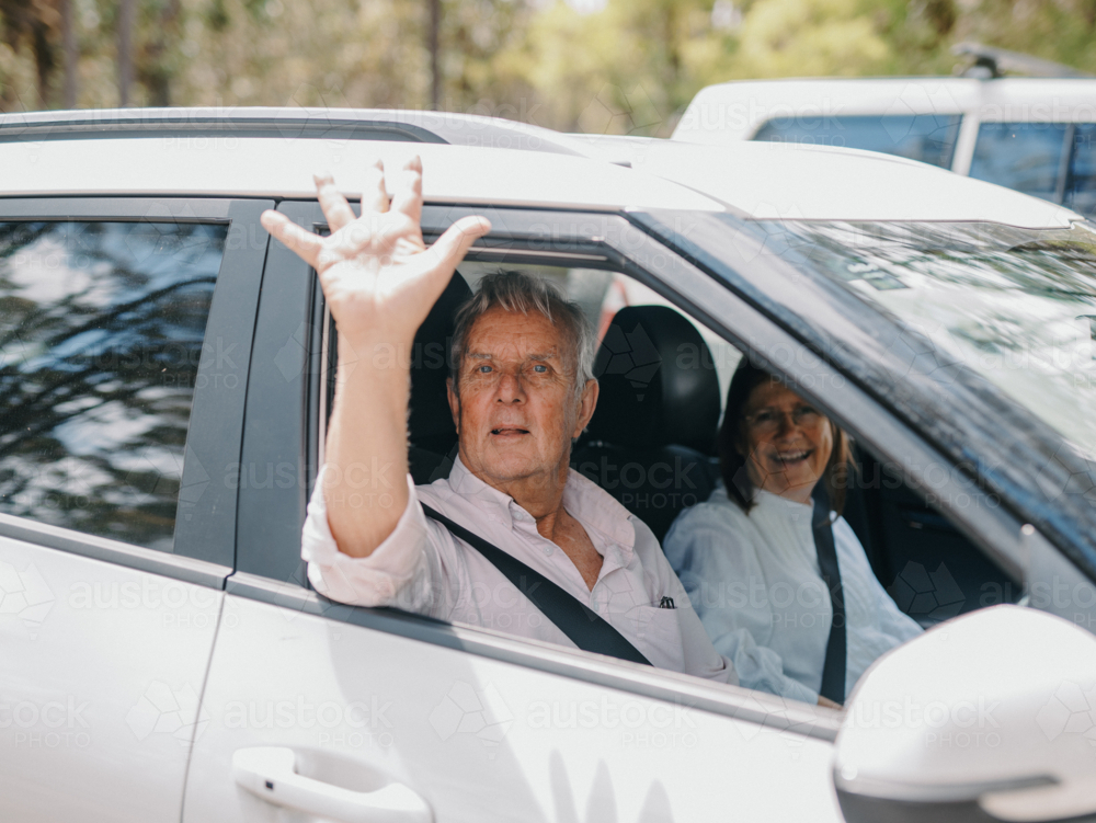 senior man waving out of car window - Australian Stock Image