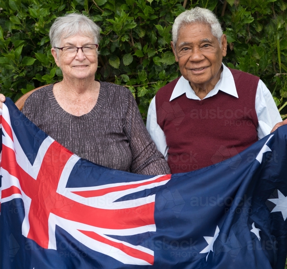 Senior married couple sitting down holding Australian flag together - Australian Stock Image
