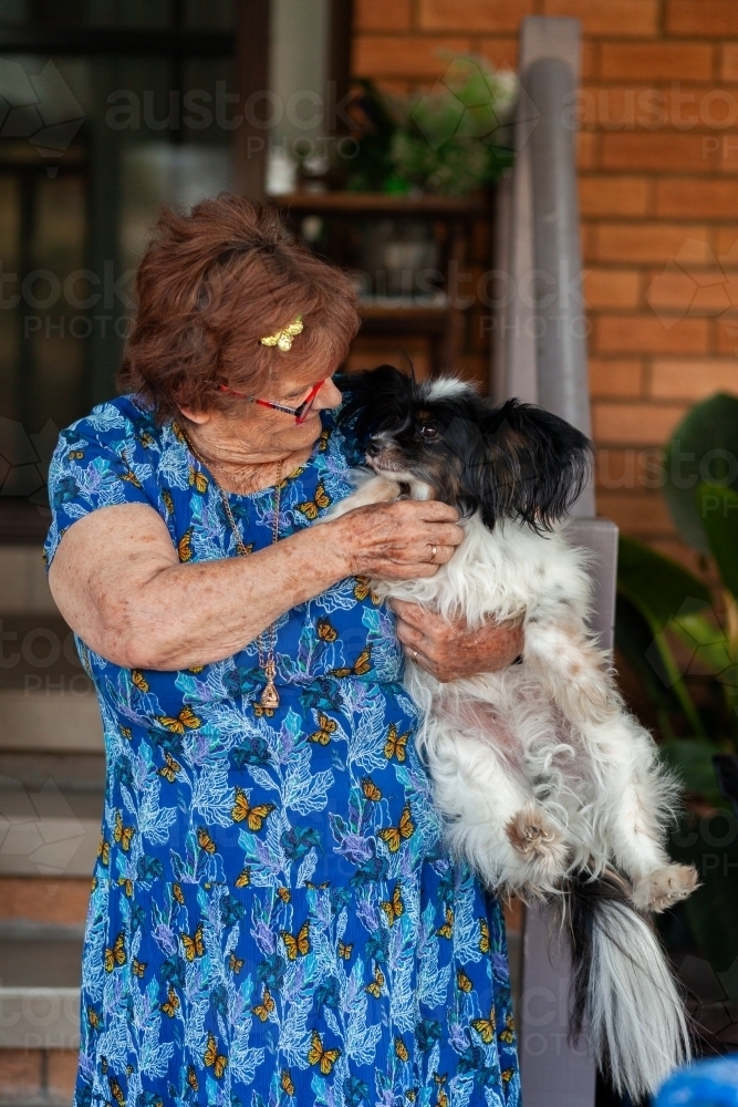 Senior woman interacting with her pet dog outside home - Australian Stock Image