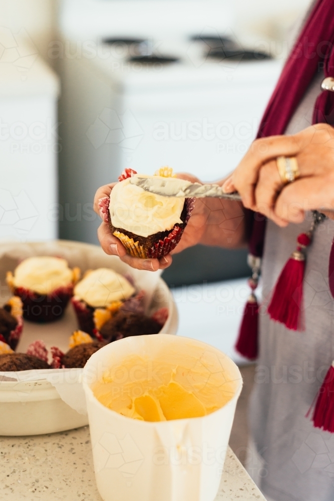 senior woman putting icing on cake - Australian Stock Image