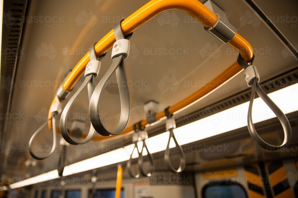 Series of handrails hanging from the ceiling of a train. - Australian Stock Image