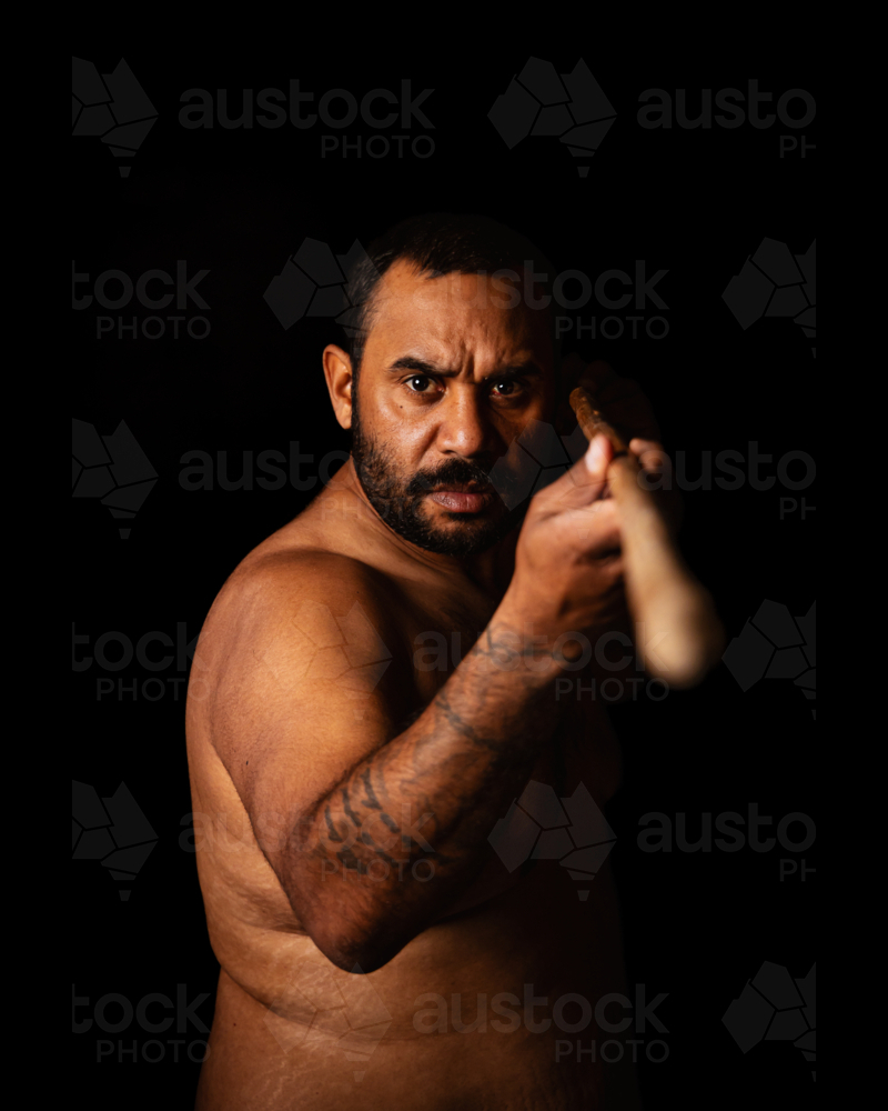 Serious Aboriginal male holding spear out with eye contact - Australian Stock Image