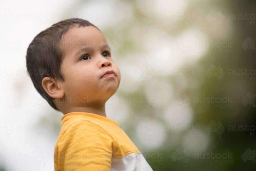Serious looking 2 year old boy looking off into the distance - Australian Stock Image