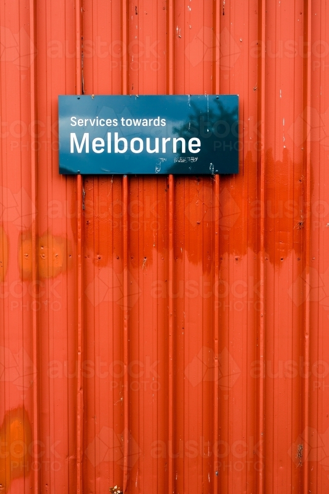 Services towards melbourne sign at a railway station on an orange wall - Australian Stock Image