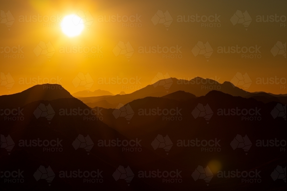 Setting sun above Mt Sonder and the West MacDonnell Ranges. - Australian Stock Image