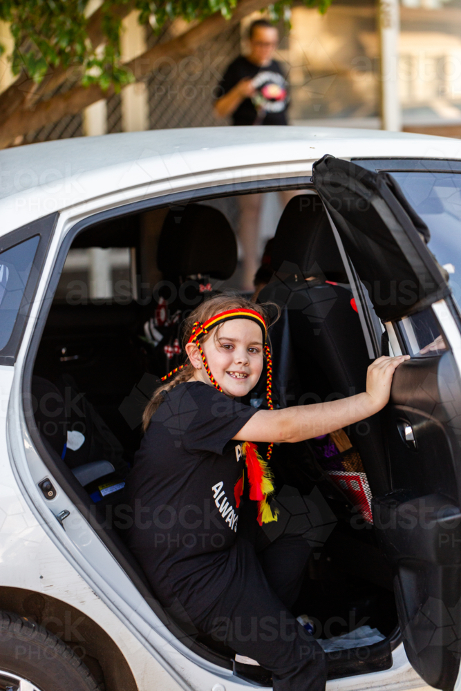 Seven year old Aboriginal girl getting into family car for trip - Australian Stock Image